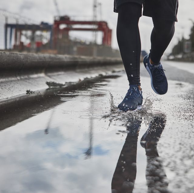close up sports shoes running on wet road stepping puddles