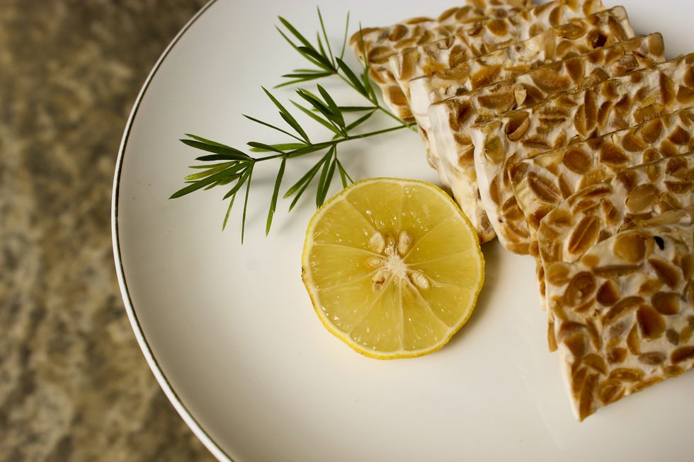 close up tempeh with orange slices on a white plate