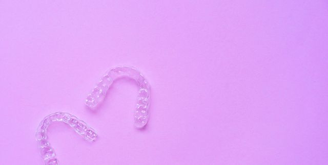 close up top view of dental aligner retainer (invisalign) on soft pastel pink color background at dental clinic for beautiful teeth treatment course concept