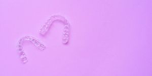 close up top view of dental aligner retainer (invisalign) on soft pastel pink color background at dental clinic for beautiful teeth treatment course concept