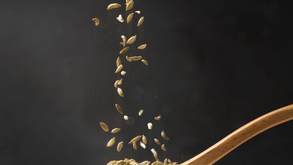 Close up view of cumin in wooden spoon.