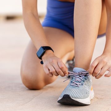 close up view of female jogger tying laces of her sport shoes before running exercise motivation, healthy lifestyle and fitness concept