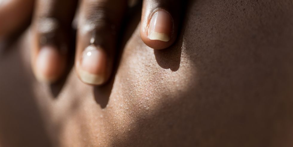 close up view of woman applying acne cream to her body at home