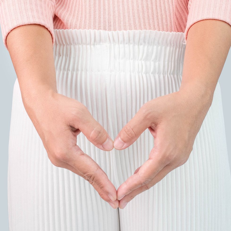 close up view of young woman and hand is a symbol of heart over her crotch feminine hygiene concept