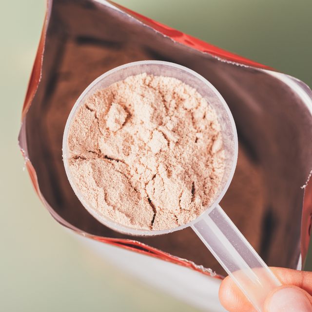close up whey protein measuring spoon over open package bag