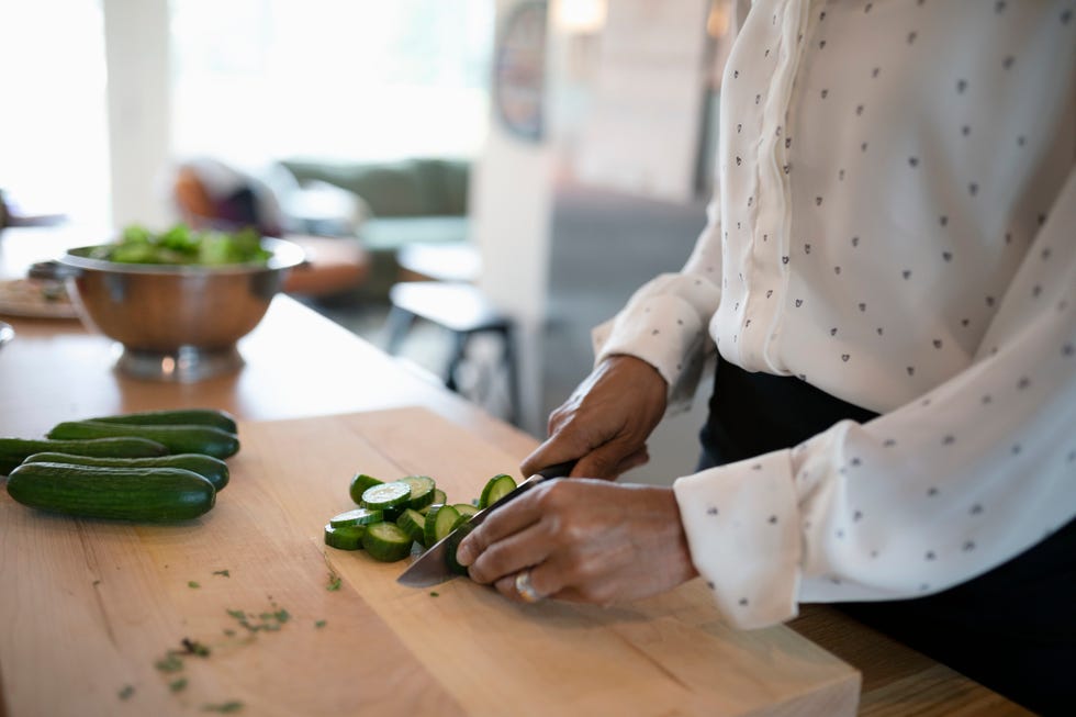 Close up woman cooking, cutting vegetables in kitchen