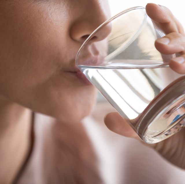 close up woman drinking pure mineral water, holding glass