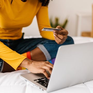 close up woman hands using credit card to buy online on laptop