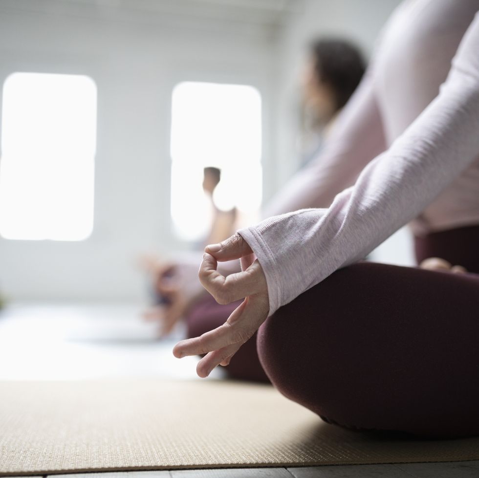 Close up woman practicing lotus position meditation with hand in gyan mudra in yoga class