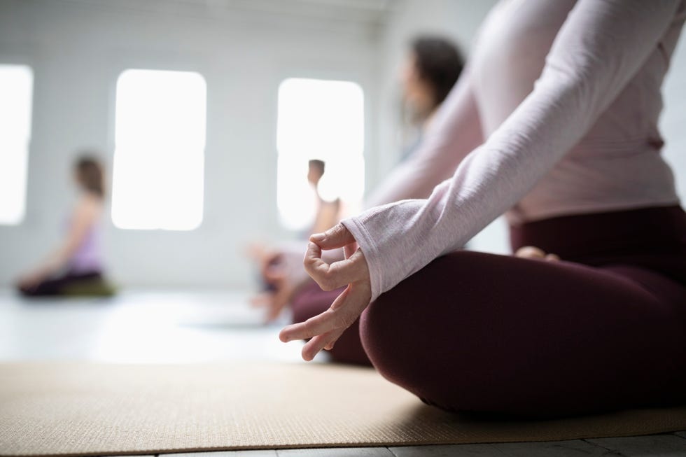 Close up woman practicing lotus position meditation with hand in gyan mudra in yoga class