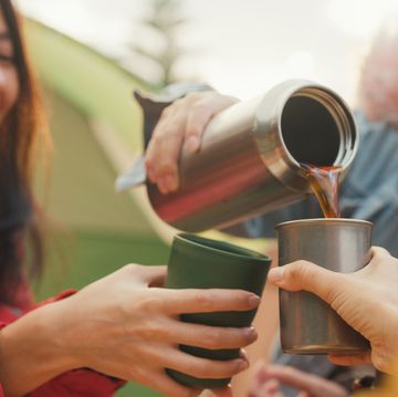 closeup group of happy asian friends drinking a cup of hot coffee for breakfast in vacation with camping caravan at morning lifestyle travel nature