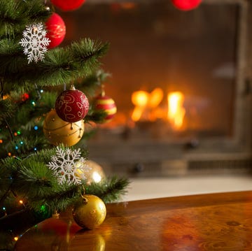 closeup image of golden baubles on christmas tree at fireplace