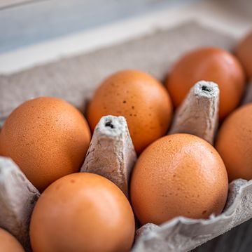closeup macro of pasture raised farm fresh dozen brown eggs store bought from farmer in carton box container with speckled eggshells texture