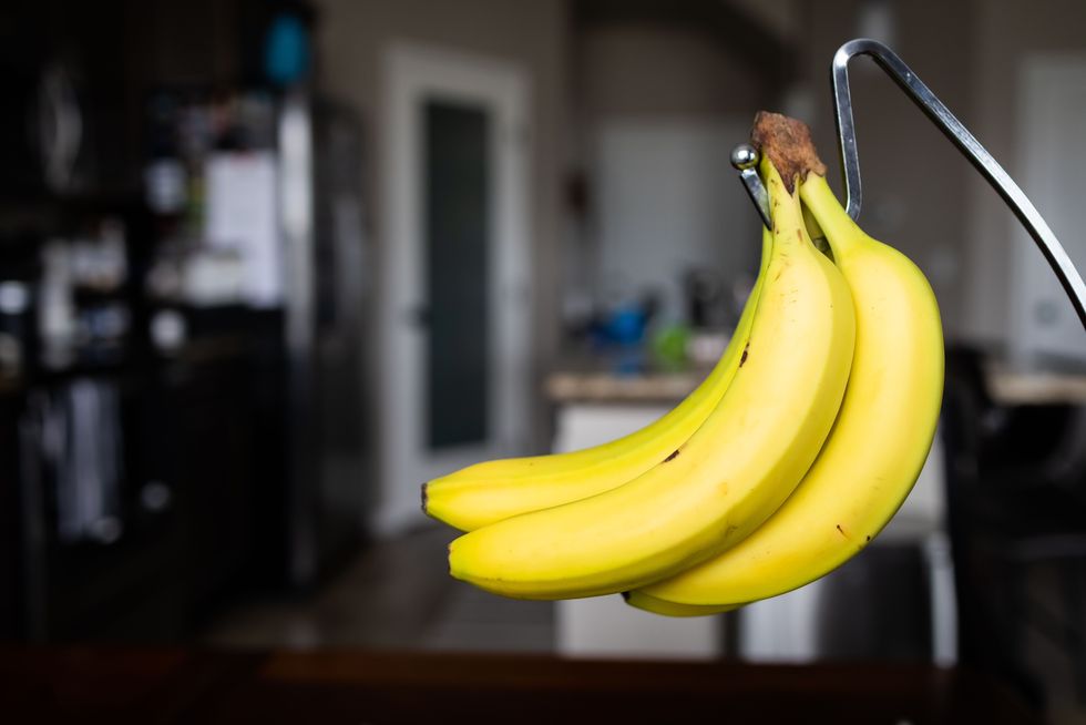 closeup of a ripe banana hanging on a banana rack in a kitchen