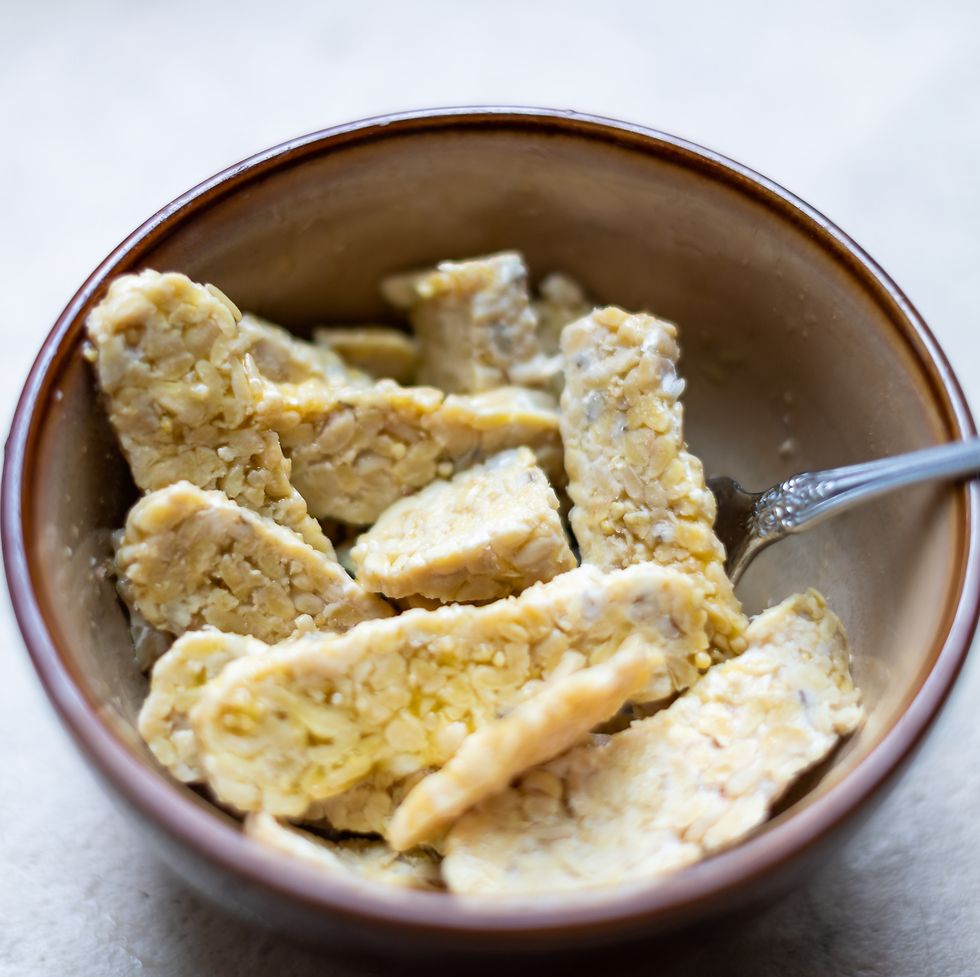 Closeup of bowl with sliced cut tempeh fermented soybeans on table cooking ingredient