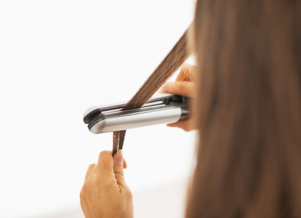 closeup on woman straightening hair with straightener