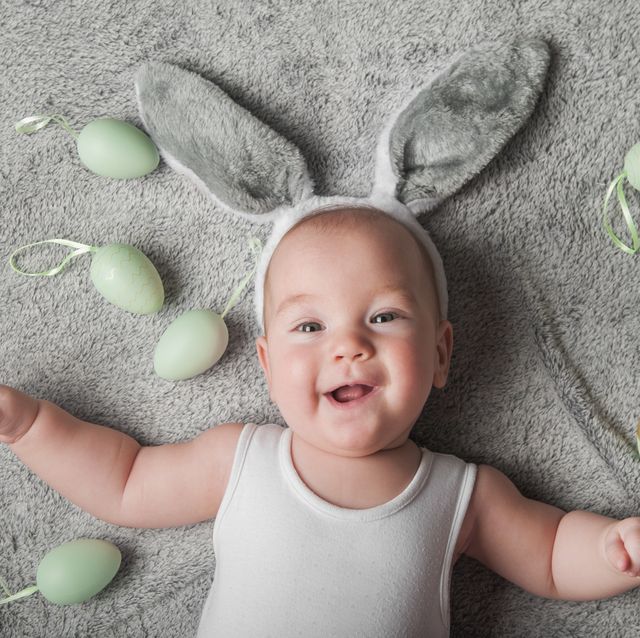 closeup portrait newborn baby 5 months old in bunny ears with easter eggs.
