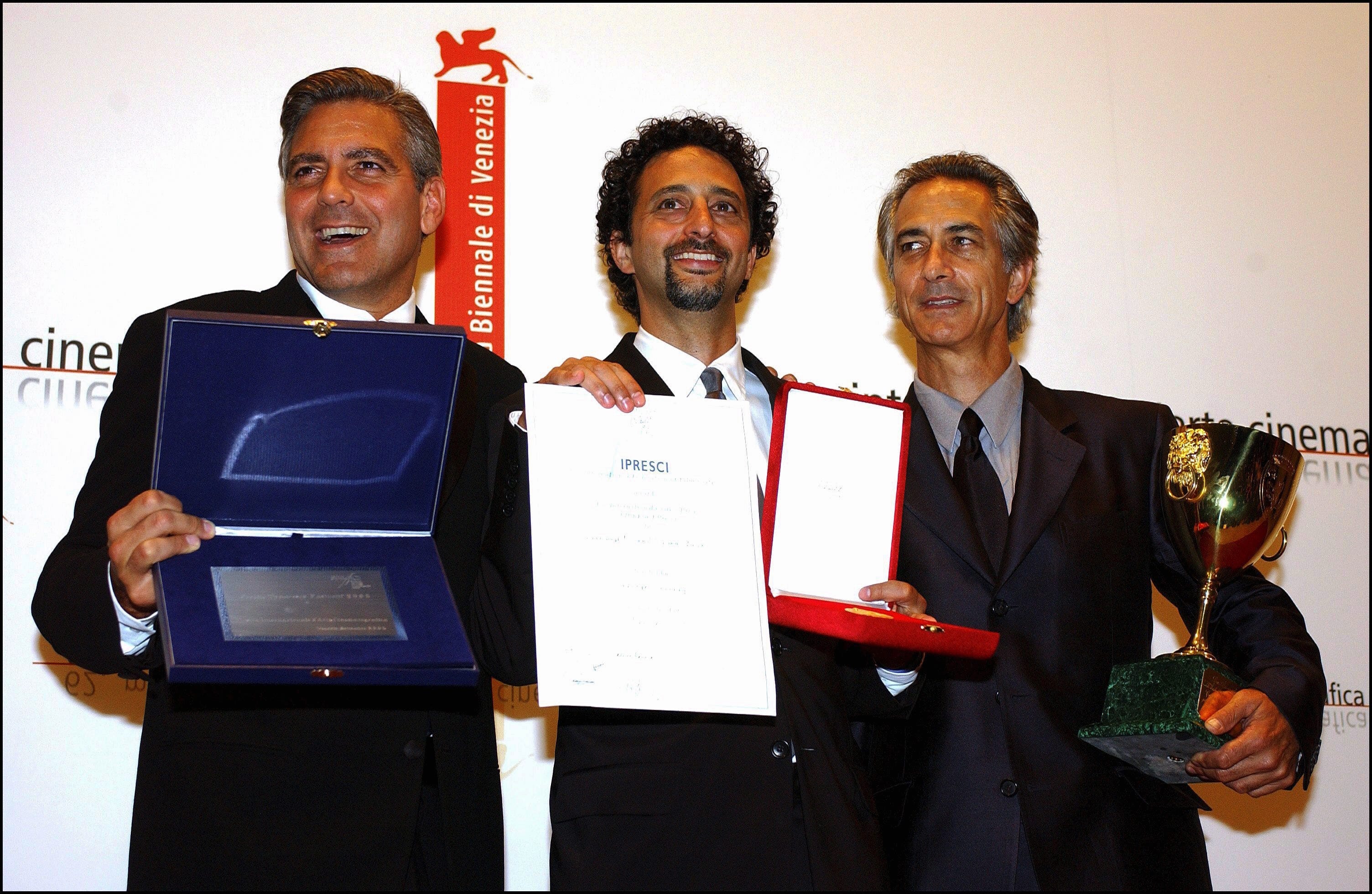 george clooney, grant heslov, and david strathairn stand together and smile as each holds a plaque or trophy