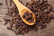 closeup of cloves in wooden teaspoon on wooden background adobe rgb color space