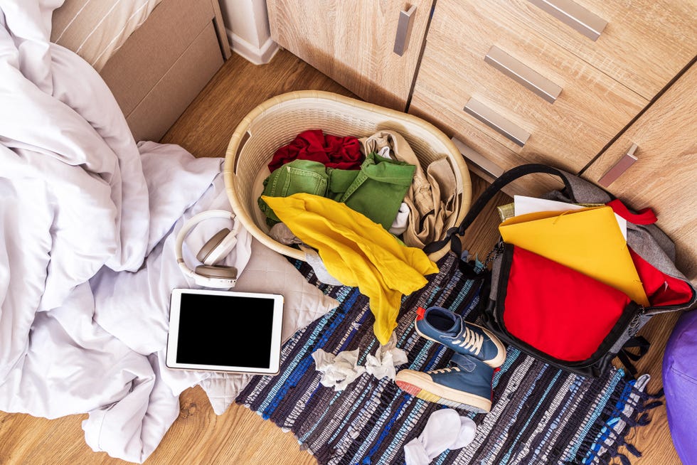 top view, close up. colored clothes, sneakers, a backpack, a blanket, a briefcase are scattered on the floor in a big mess.
