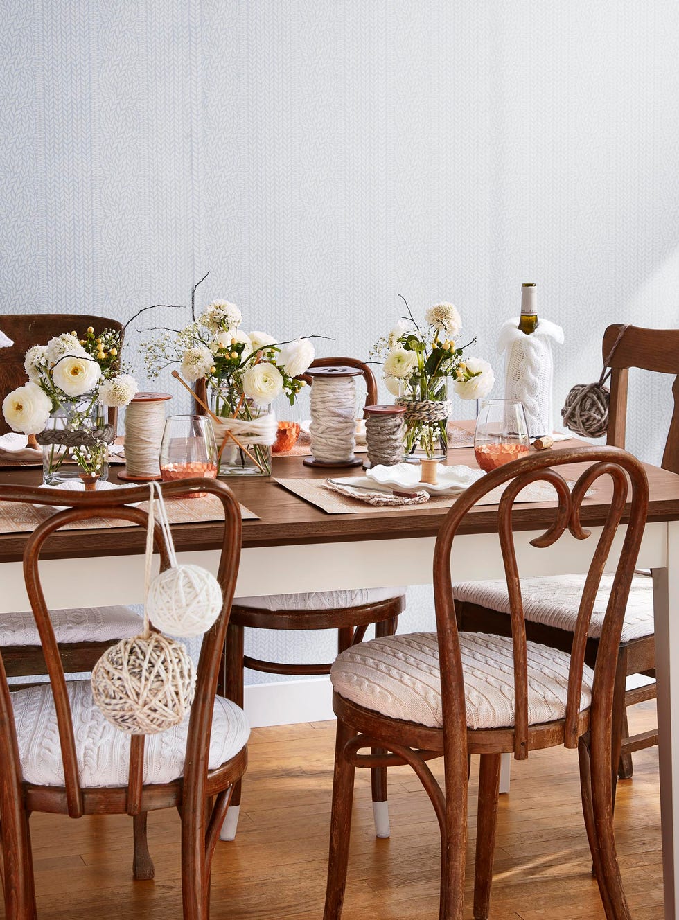 wood table with table set for a winter dinner party complete with cableknit covered bistro chairs