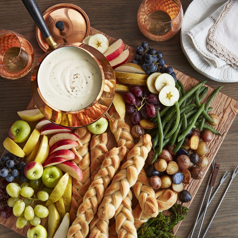 a breadboard filled with bread and fruit and melted cheese