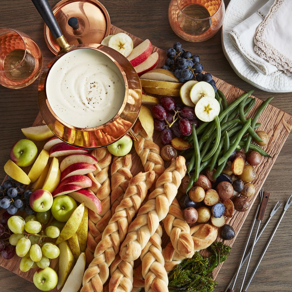 a breadboard filled with bread and fruit and melted cheese