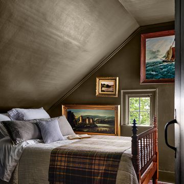 bedroom drenched in brown paint with a hint of green, antique wood bed, oil paintings on the wall, ticking stripe bedding with plaid blanket