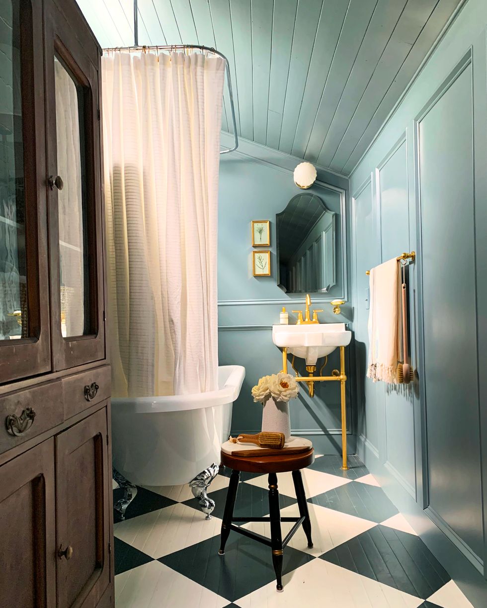 vintage furniture in bright blue bathroom with painted dark blue and white checkered floors