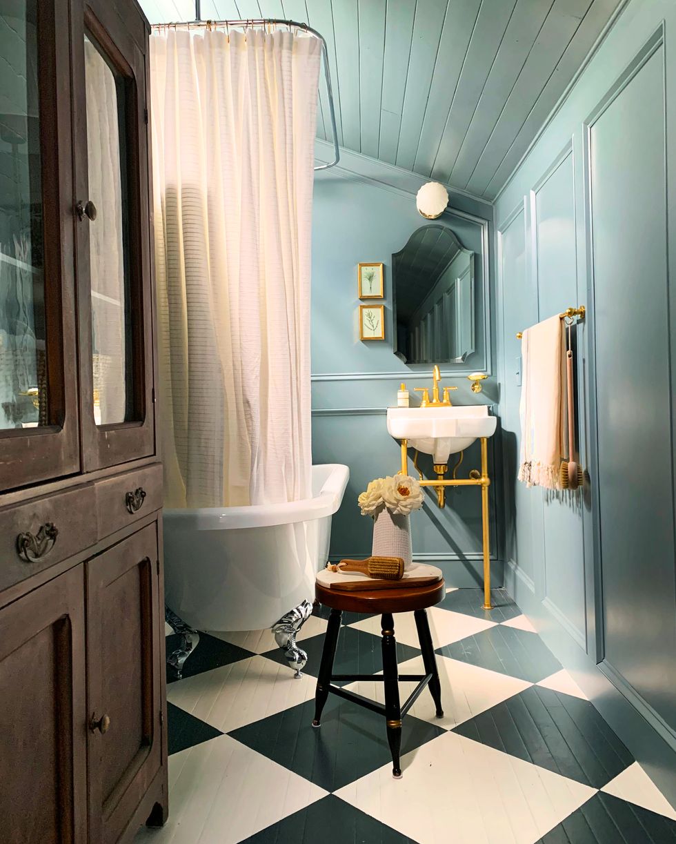 vintage furniture in bright blue bathroom with painted dark blue and white checkered floors