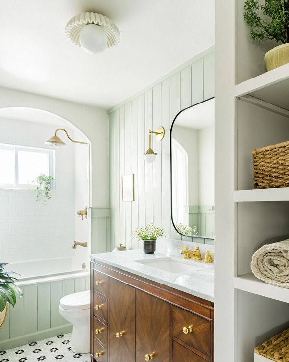 a bright and airy bathroom with a drop in tub, walnut wood vanity, and mirror