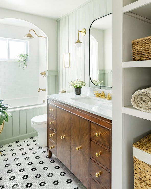 a bright and airy bathroom with a drop in tub, walnut wood vanity, and mirror