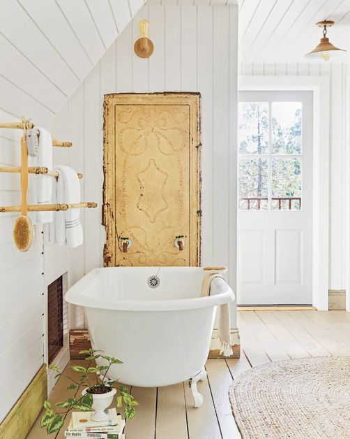 bright white bathroom in country home with a white cast iron tub and tan painted wood floors