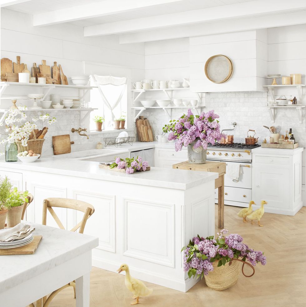 a white farmhouse kitchen with purple flowers and live ducks on the floor