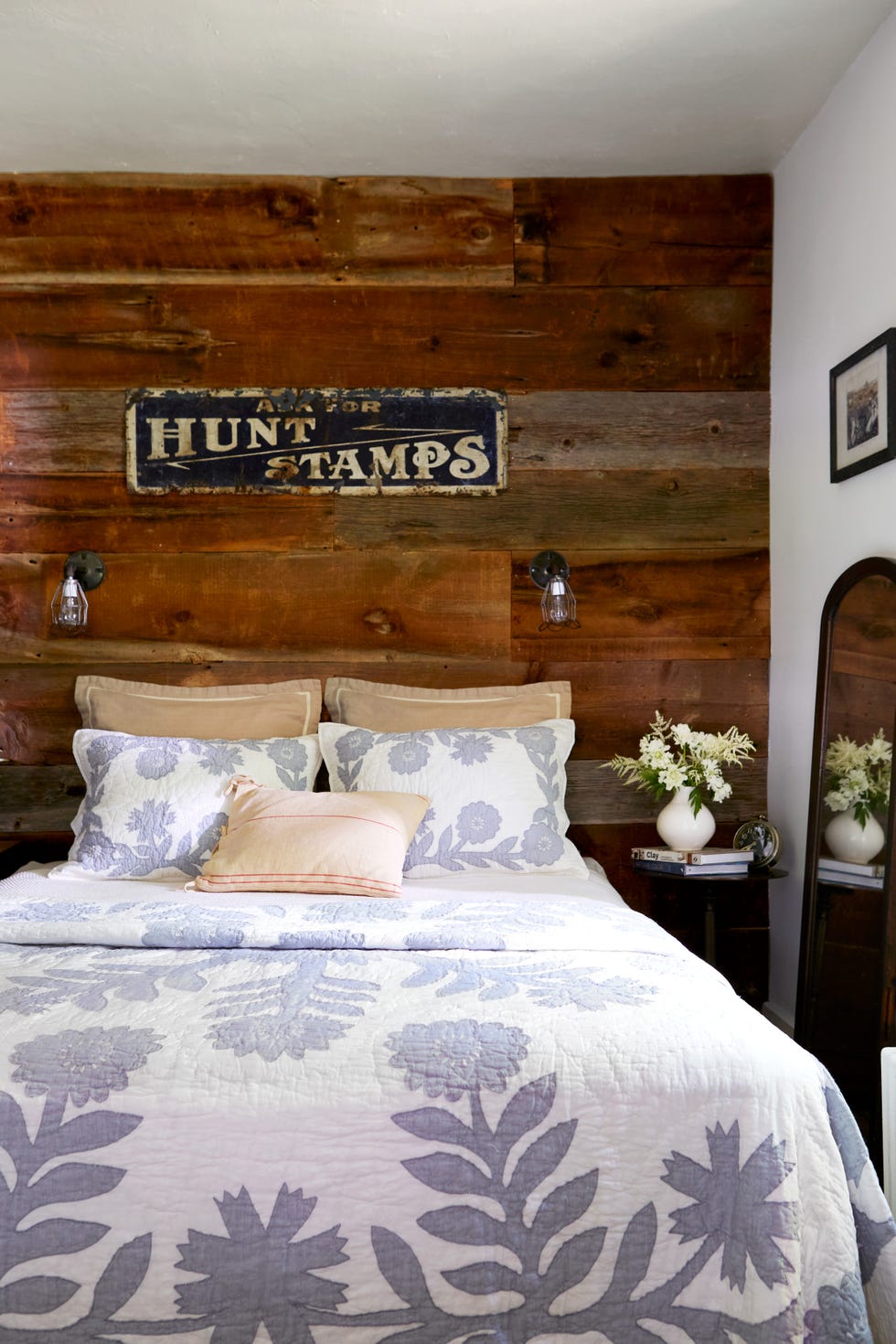 white and lavendar bedding in front of a reclaimed wood wall