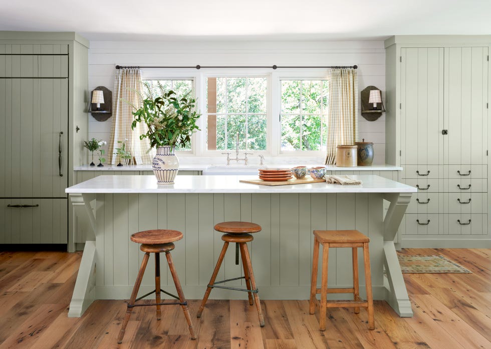 Lakeside home kitchen with green-gray cabinets and a marble-top island