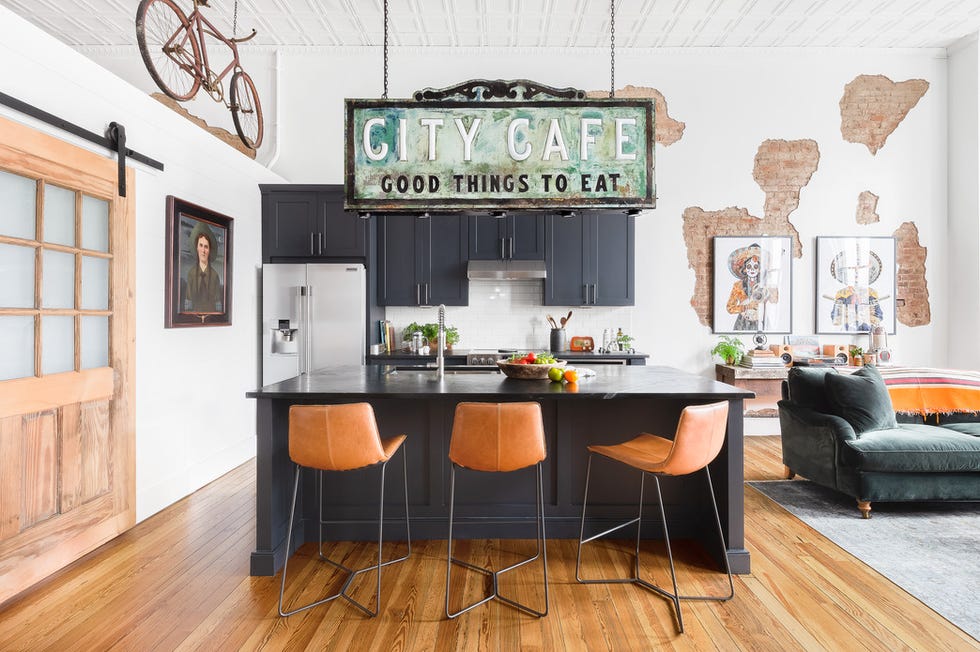 kitchen with black painted island and black stone counters, leather bar stools