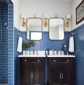 bathroom with blue subway tile in the shower, blue paint on the wainscoting and oversized black and white hex tiles