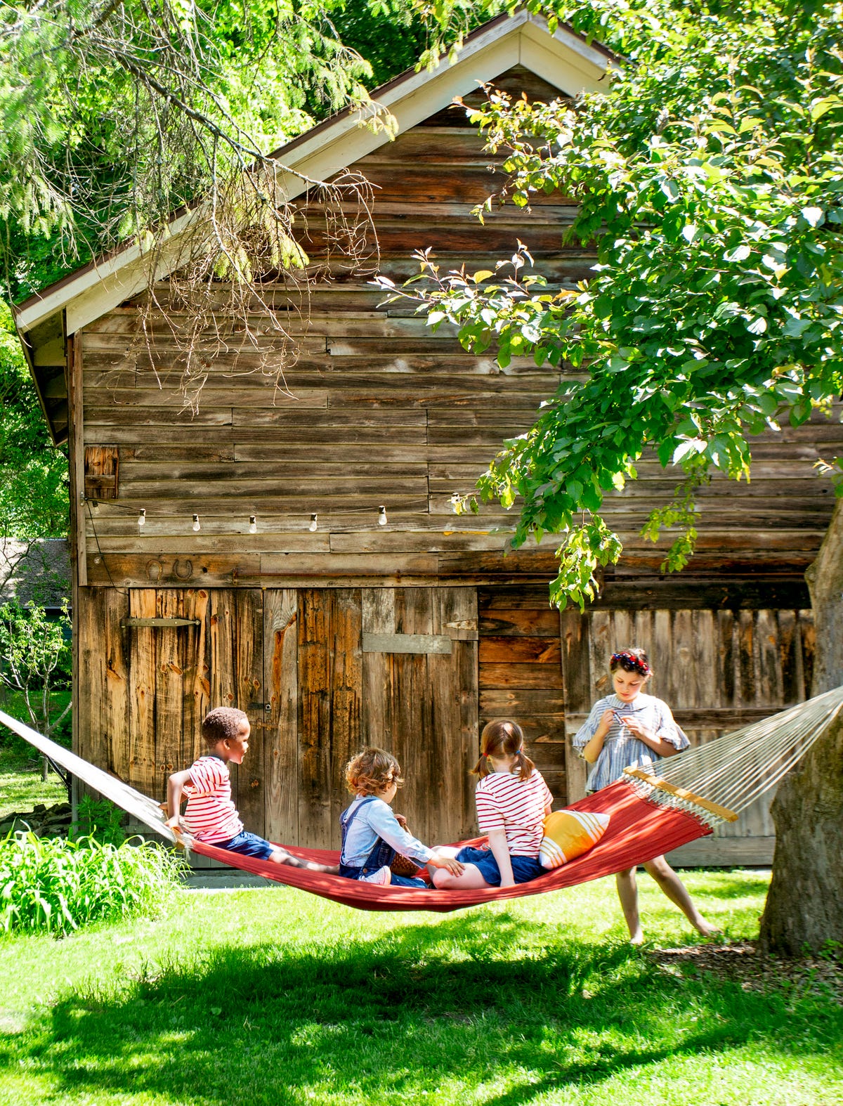 kids on a hammock in front of a barn