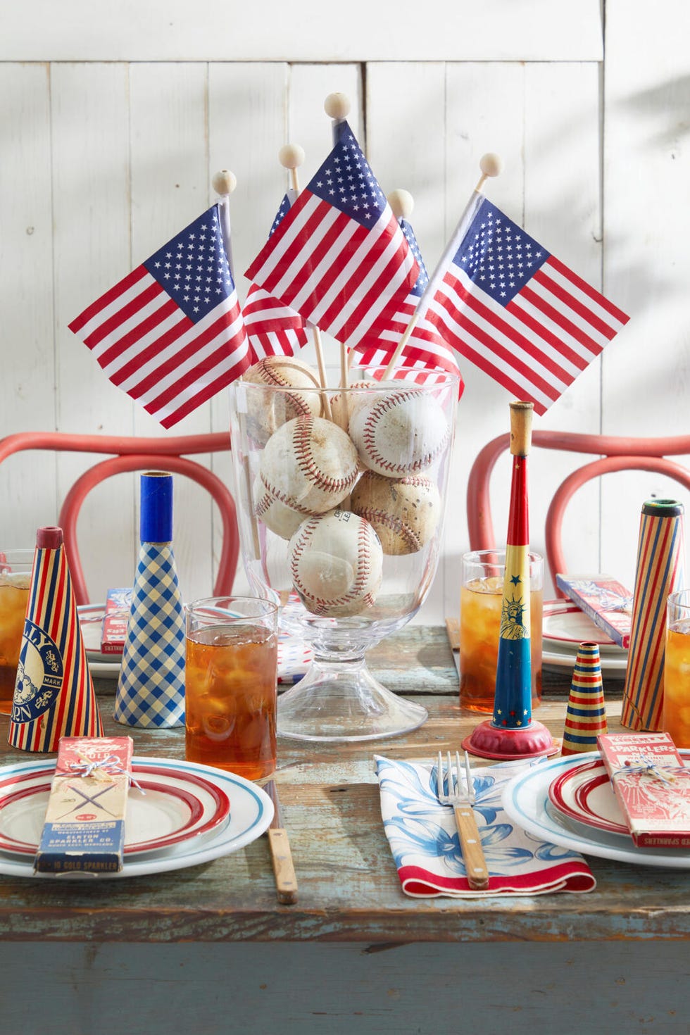 A table with various flags placed inside a glass container containing a baseball