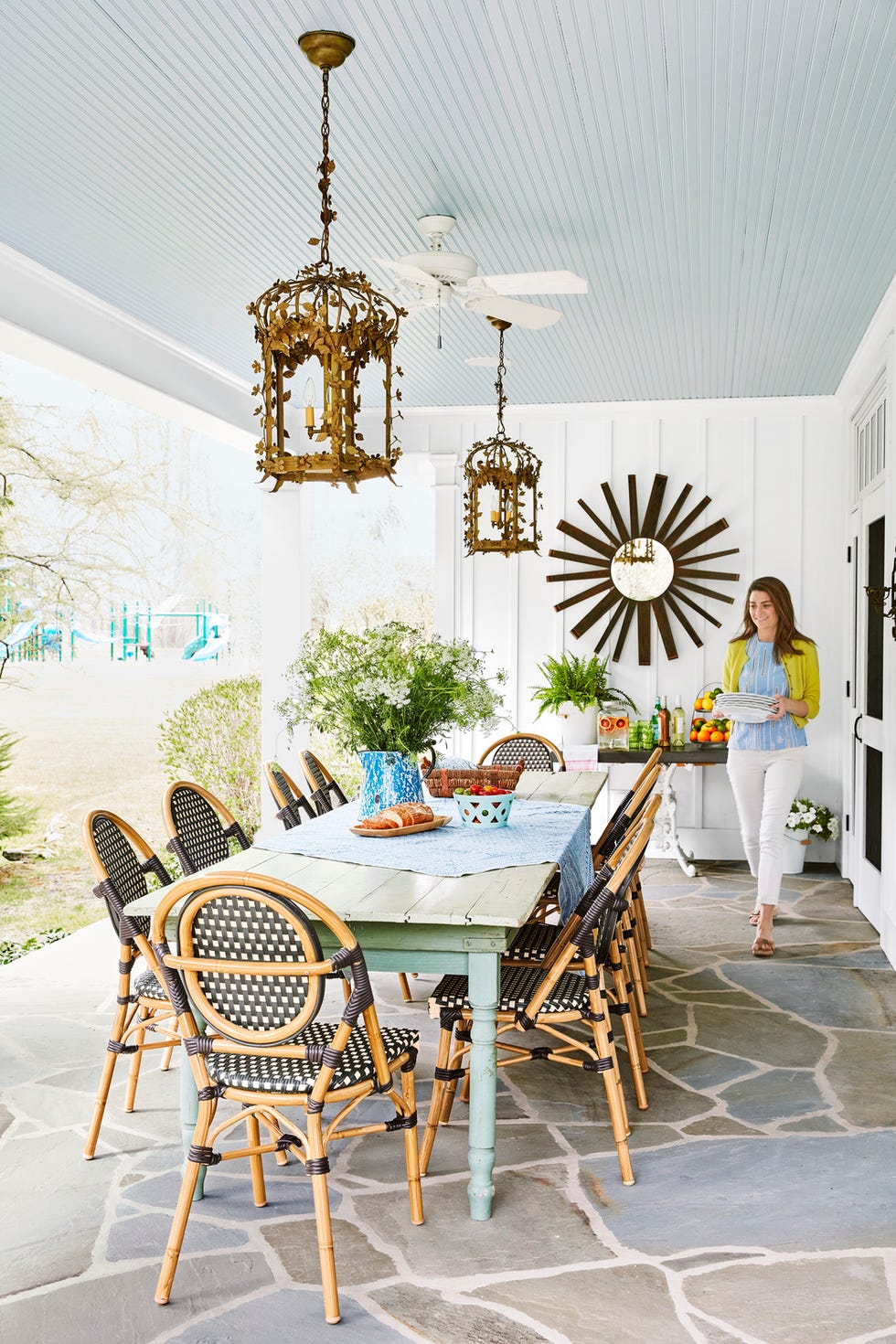covered outdoor dining room with long table, black and white bistro chairs