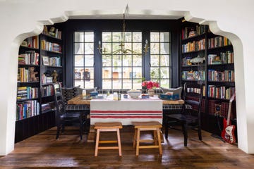 dining room alcove painted dark black with bookcases on each end and big wood table in the middle