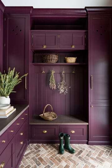 a dark purple mudroom with brick herringbone floors