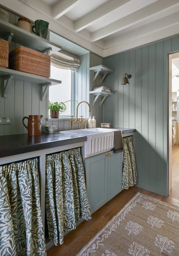 scullery and laundry room with blue walls, black counter top, and three skirted cabinets