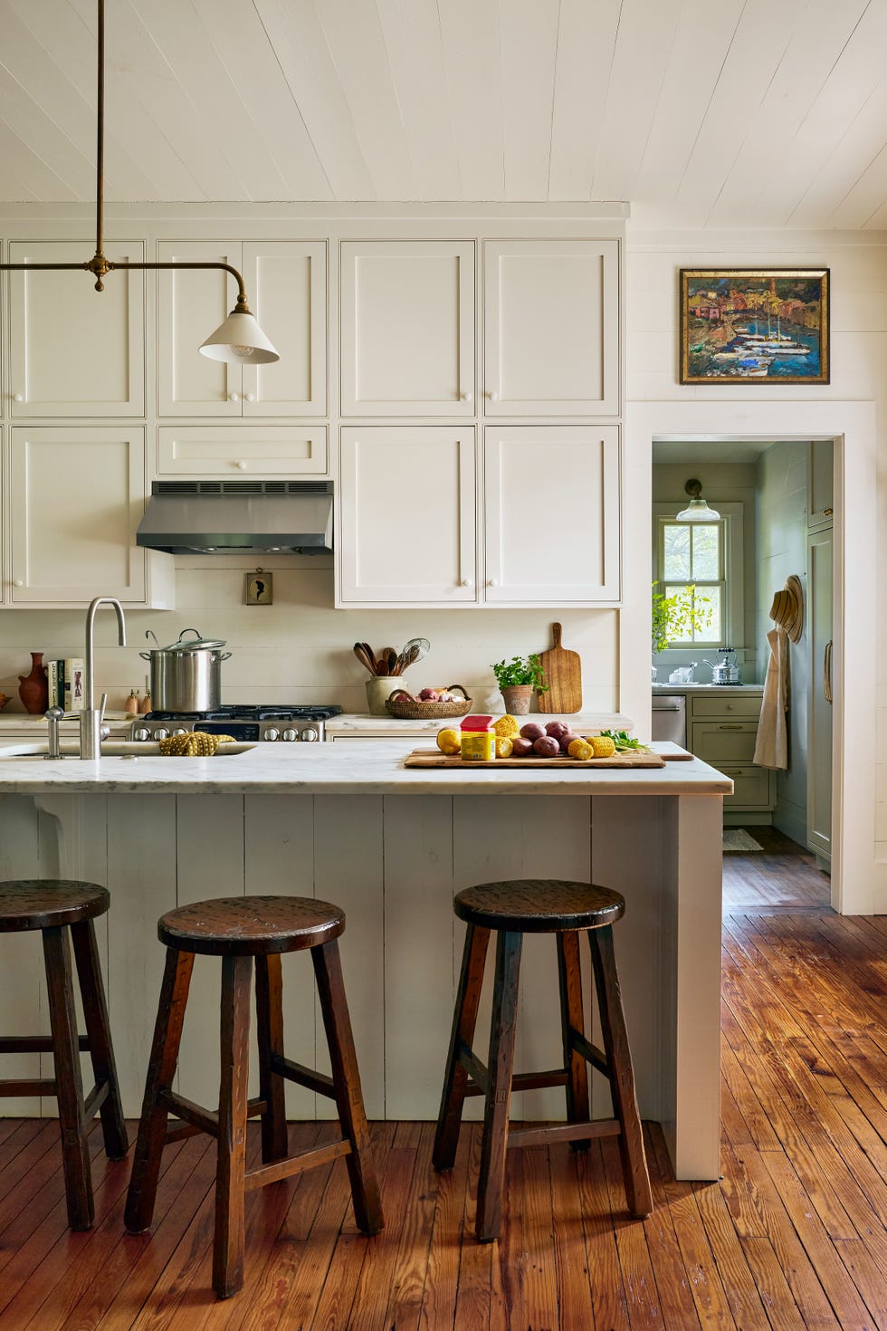 white farmhouse kitchen with shaker cabinets, marble island, three wooden rustic counter stools at island