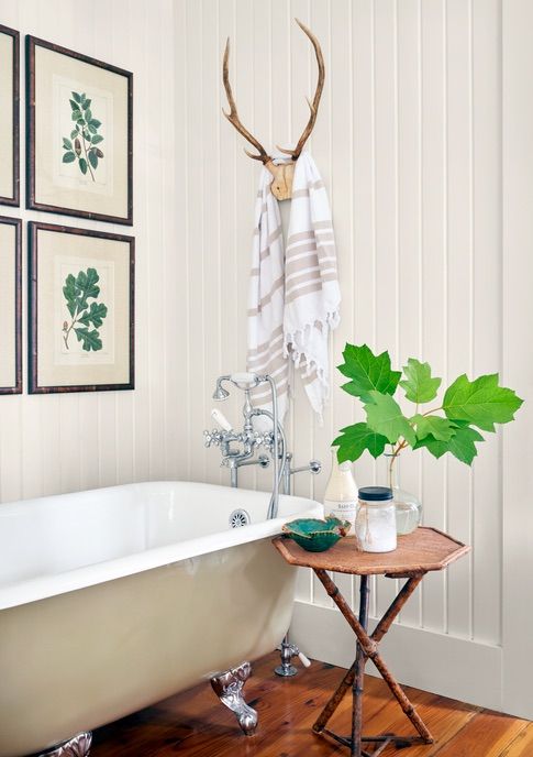 white beadboard bathroom with tan clawfoot tub and octagonal bamboo table