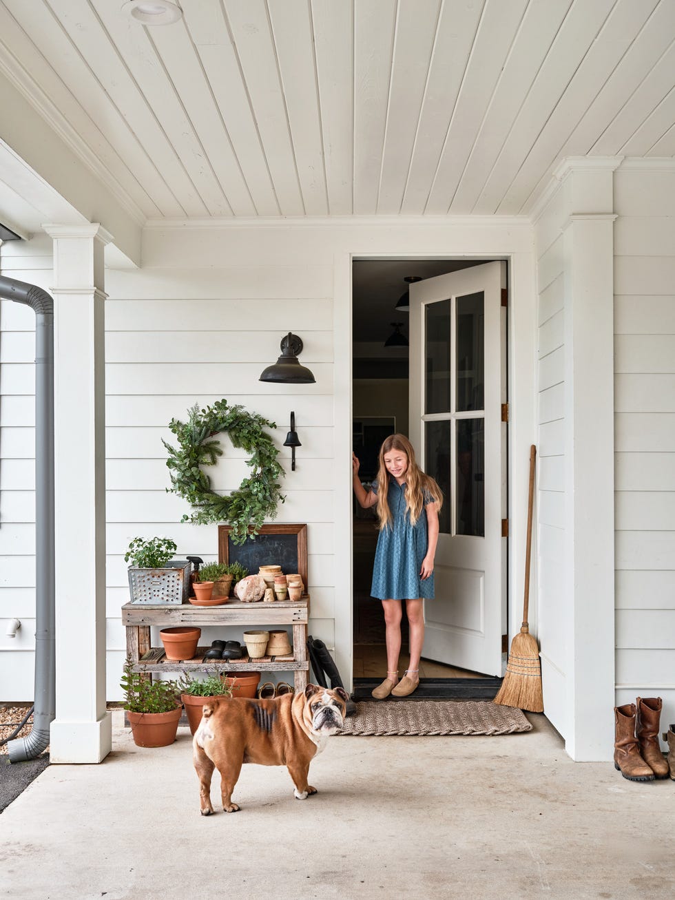 porch with a potting station next to door and girl and dog standing