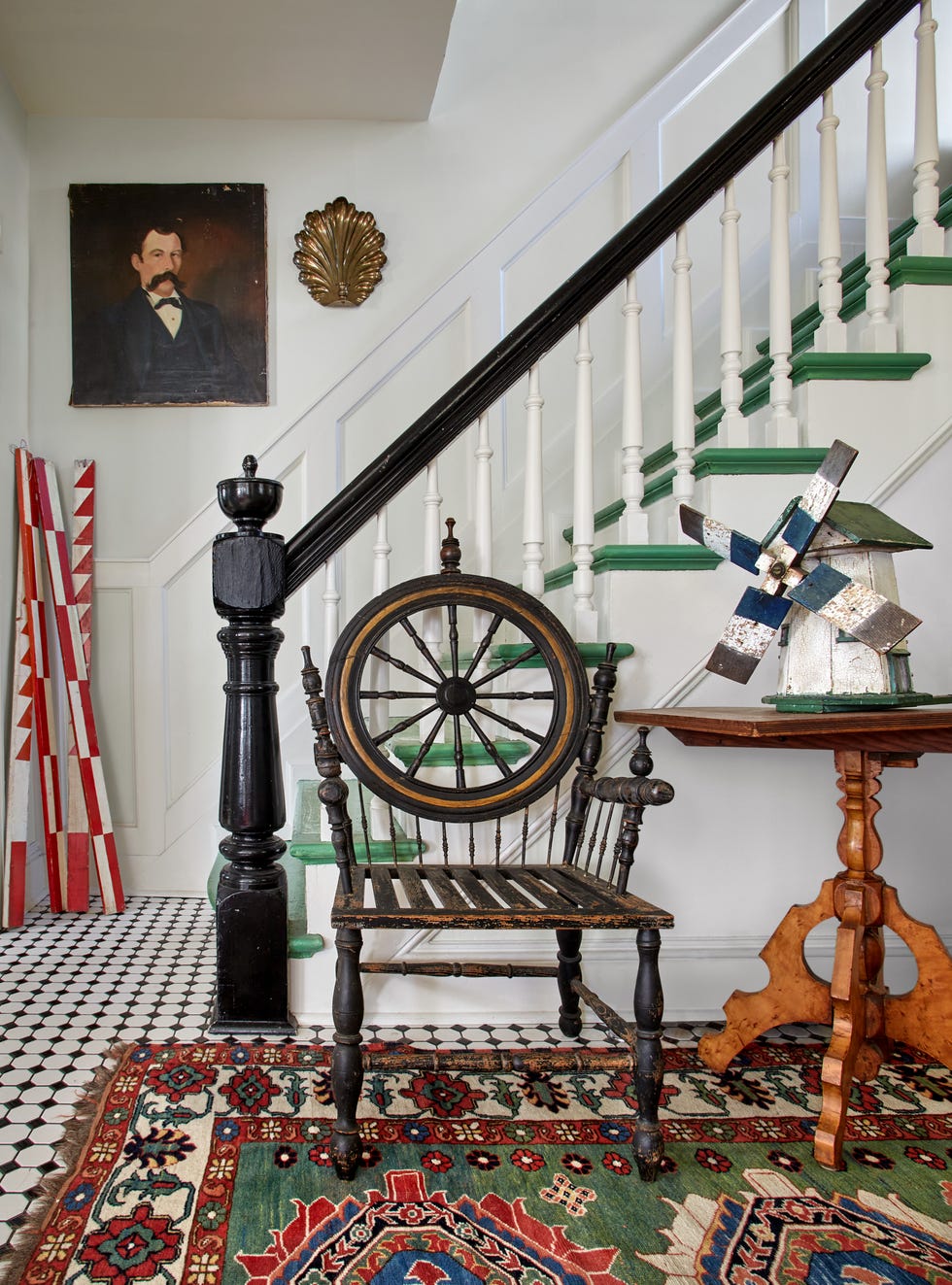 white stairwell filled with antiques, stair treads are painted a classically true green