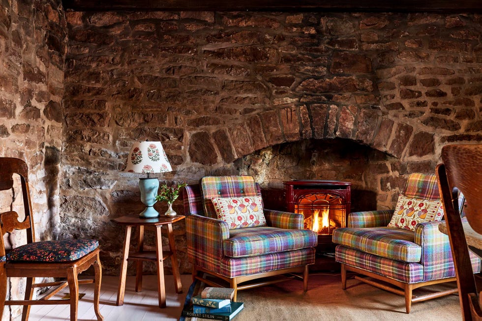 stone fireplace with two plaid armchairs in front