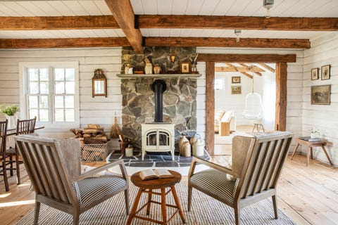 white living room in a cabin with stone fireplace with wood burning stove